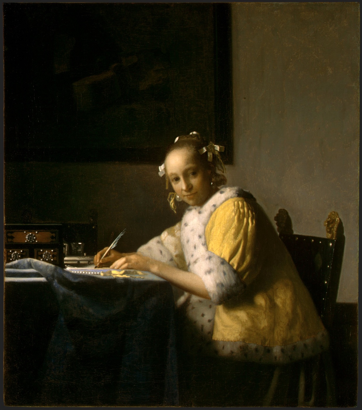 A Lady Writing, Johannes Vermeer, c.1665 — a young woman in a yellow jacket pauses mid-letter, quill in hand, to meet the viewer's gaze.